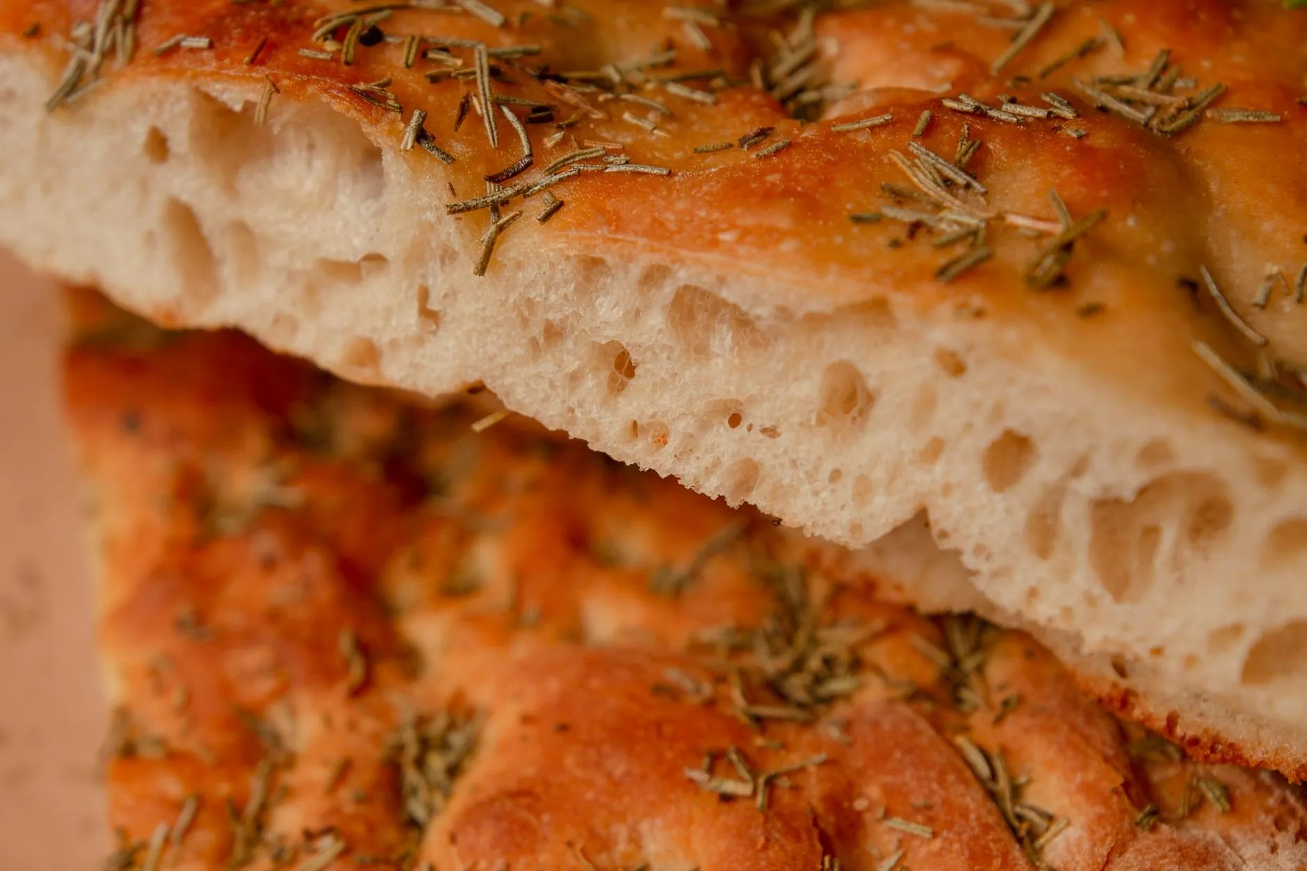 A close view of rosemary focaccia with a golden top and an open, airy crumb